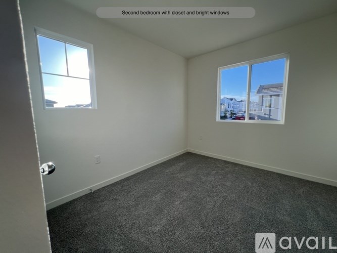A second bedroom with a view of the street outside through the windows.