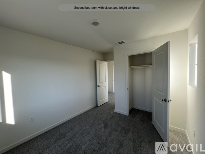 A room with a carpeted floor and two doors, one of which is open.