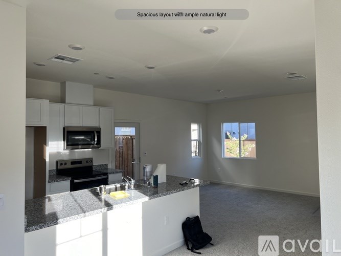 A spacious kitchen with granite countertops and a backpack on the floor.