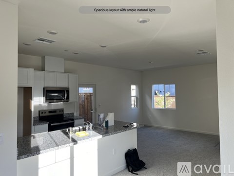 A spacious kitchen with granite countertops and a backpack on the floor.