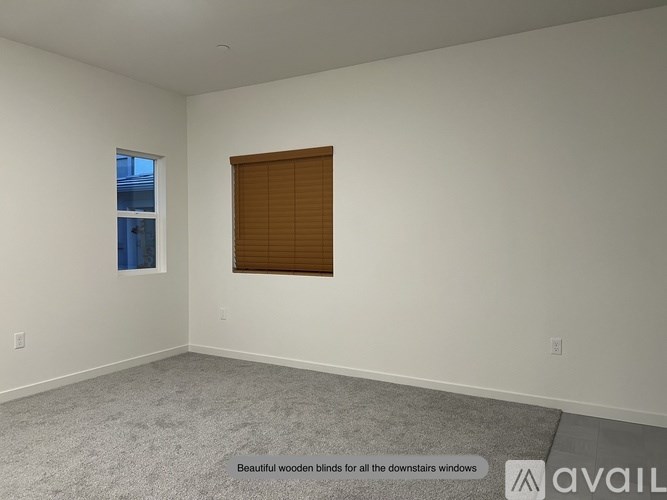 A room with a window covered by wooden blinds.