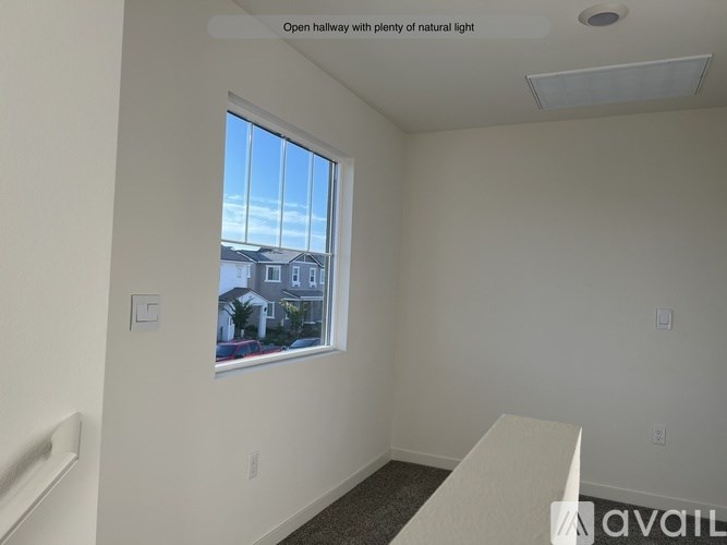 A room with a large window and a view of a house across the street.