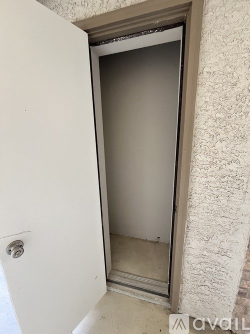 A white door with a silver handle is open to a room with a beige wall.