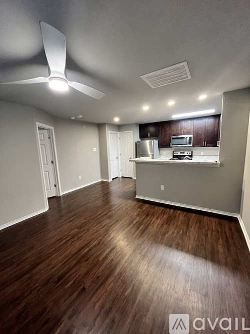 A room with a ceiling fan and wooden flooring.