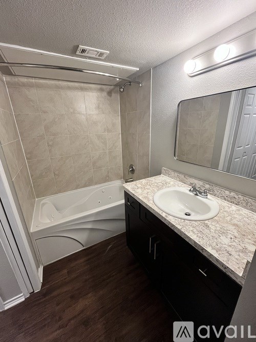 A bathroom with a tub, sink, and mirror.
