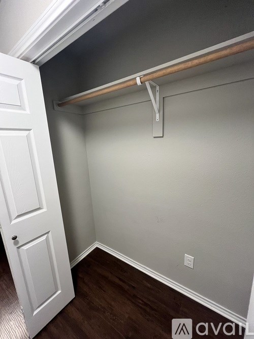A white door is open to a room with a wooden floor and a white wall.