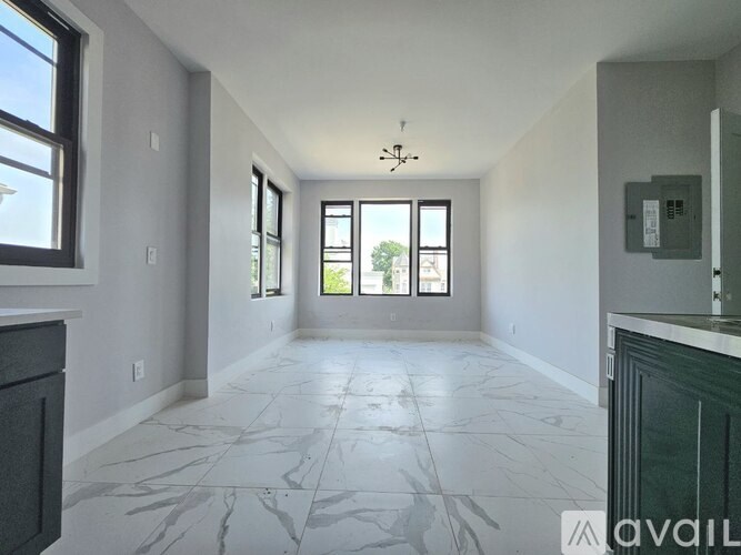 A spacious room with marble flooring and large windows.