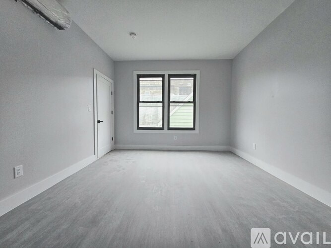 A spacious empty room with a window and a door.