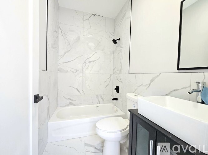 A white bathroom with a marble wall and a white toilet.