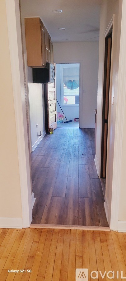 A long hallway with wood floors and white walls.