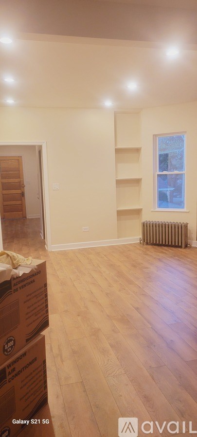A room with wooden floors and a window with a radiator to the side.