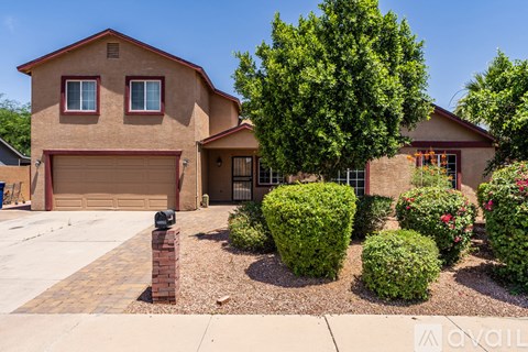 A house with a brown garage door and a brick pillar in front of it.