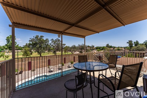 A patio with a table and chairs overlooking a pool.