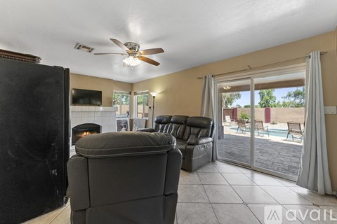 A living room with a black couch and a ceiling fan.