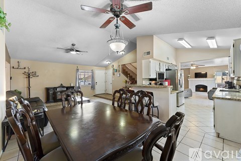 A kitchen with a table and chairs in the foreground and a staircase in the background.