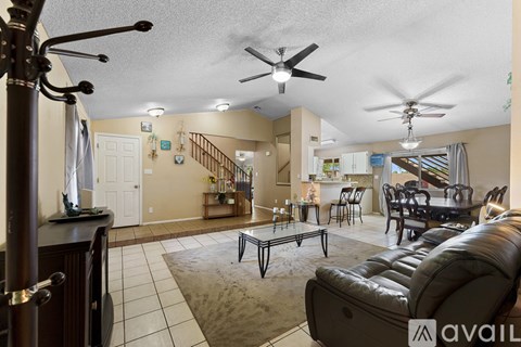 A living room with a black leather couch and a rug.