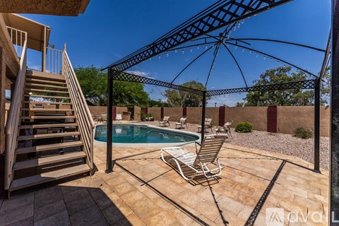 A patio with a pool and a chair under a canopy.