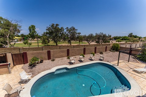 A swimming pool surrounded by a fence and chairs.