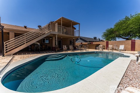 A pool in a backyard with a deck and a house in the background.