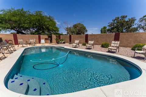 A pool with a hose in it and chairs around it.