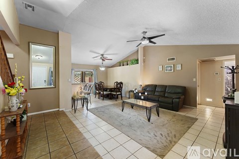 A living room with a black couch and a fan on the ceiling.