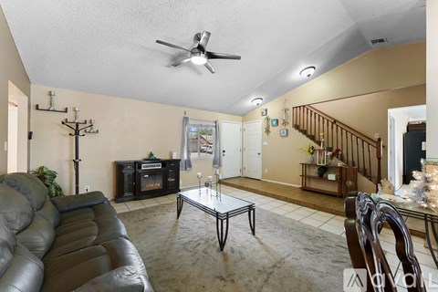 A living room with a black leather couch and a glass coffee table.