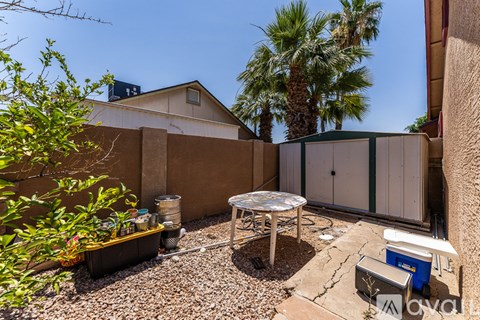 A backyard with a table and chairs and a fence.