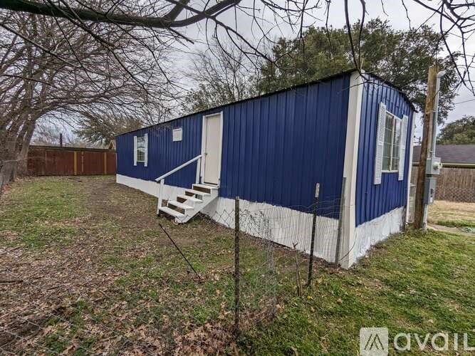 A blue and white mobile home with a white door and stairs.