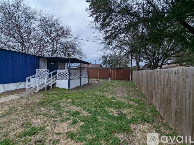 A blue building with a white fence and a wooden fence in the backyard.