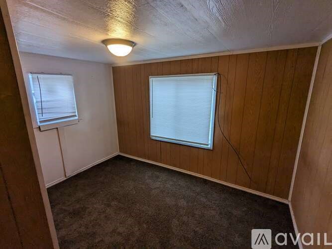 A room with a window and a carpeted floor.