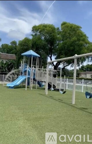 A playground with a blue slide and a white fence.