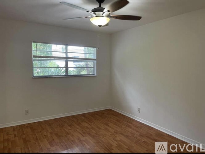 A room with a ceiling fan and a window with blinds.