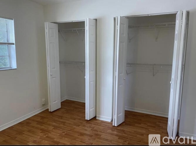 Three white closets in a room with wood floors.