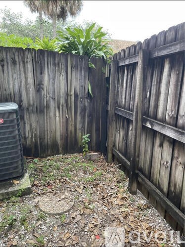 A backyard with a wooden fence and a tree in the corner.