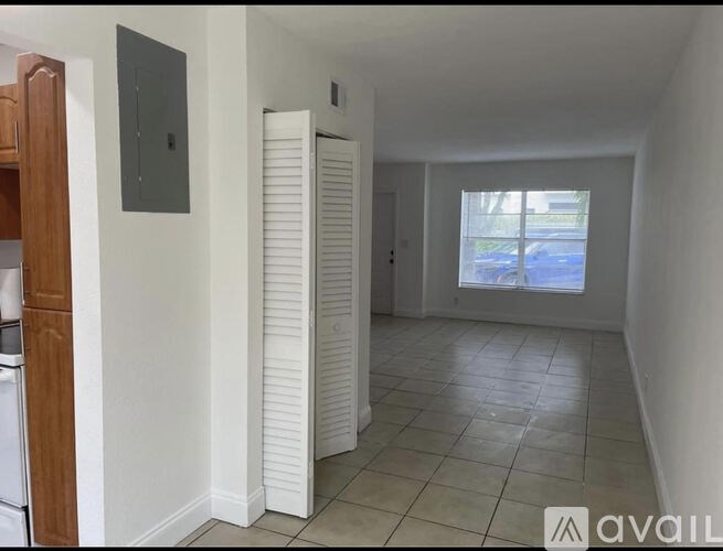 A room with a white door and a window with a view of a parking lot.