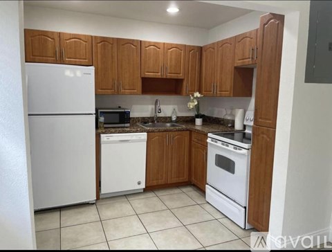 A kitchen with white appliances and wooden cabinets.