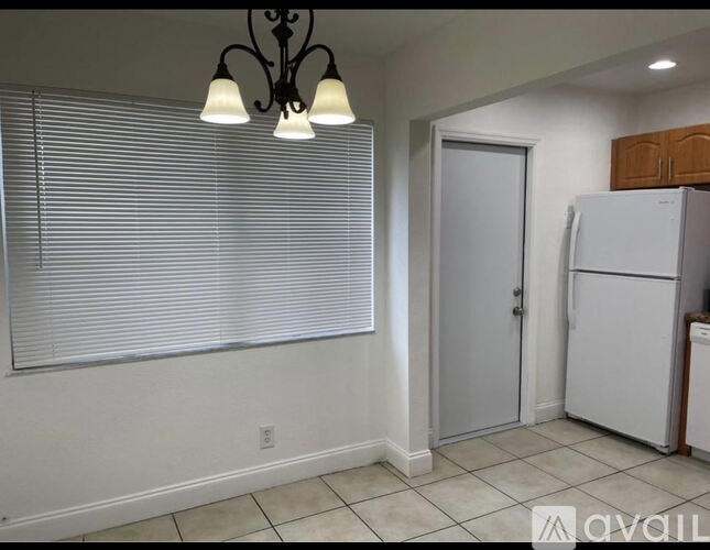 A kitchen area with a white fridge and a door.