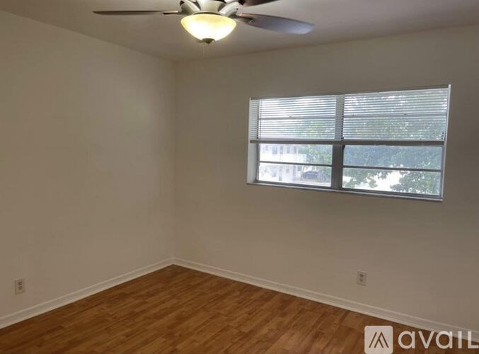 A room with a ceiling fan and a window with blinds.