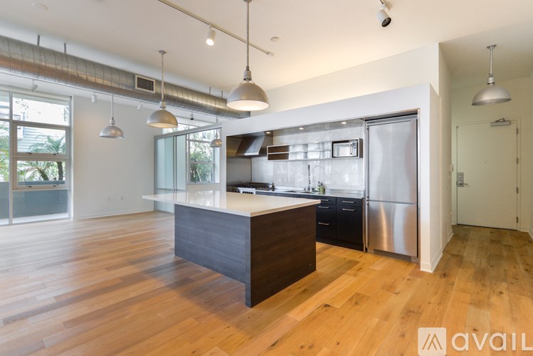 A modern kitchen with wooden floors and stainless steel appliances.