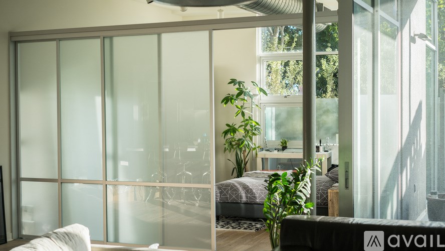 A room with a glass wall and a bed in the background.