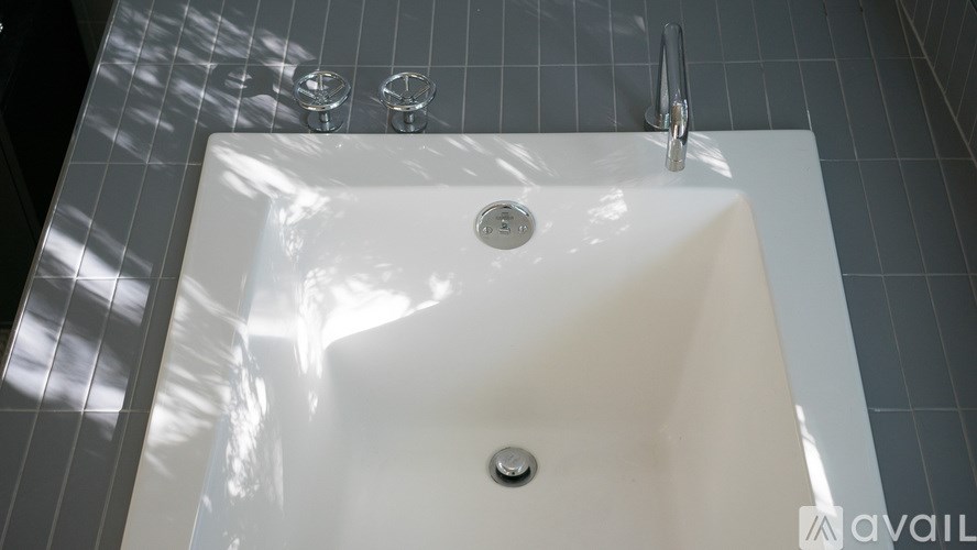 A white sink with a silver faucet and two glasses on the counter.