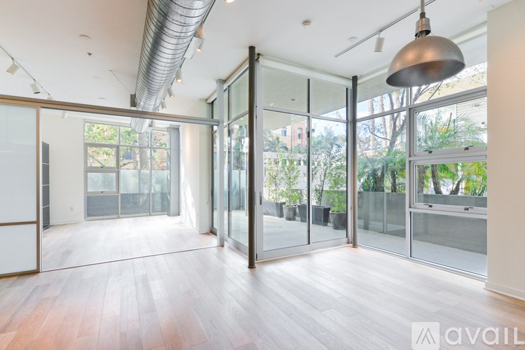 A spacious room with wooden floors and large glass doors leading to a balcony.