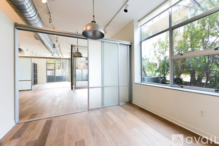 A room with a wooden floor and a glass door leading to another room.