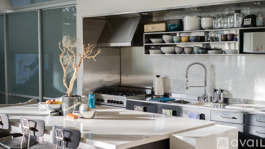A modern kitchen with a white countertop and black chairs.