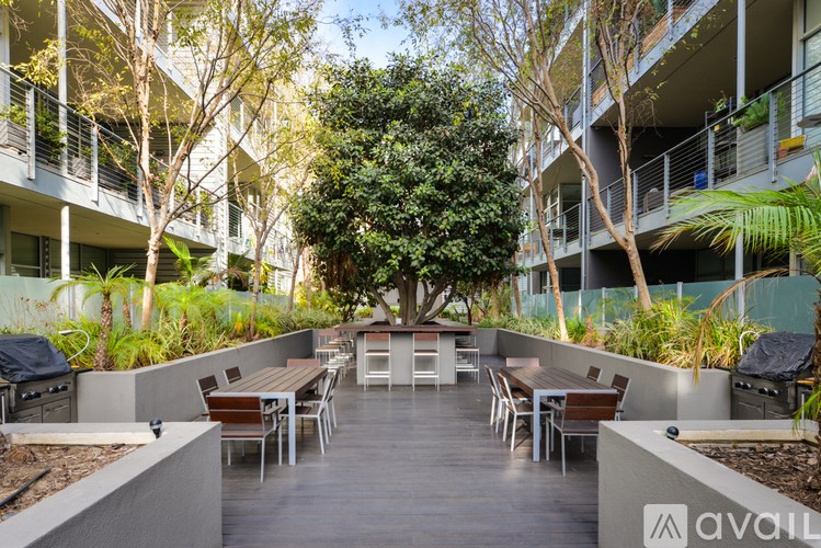 A patio with a table surrounded by chairs and a tree in the middle.