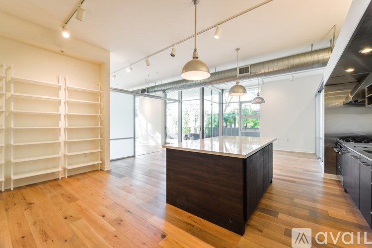 A spacious room with a wooden floor, a reception desk, and a large window with a view of trees outside.