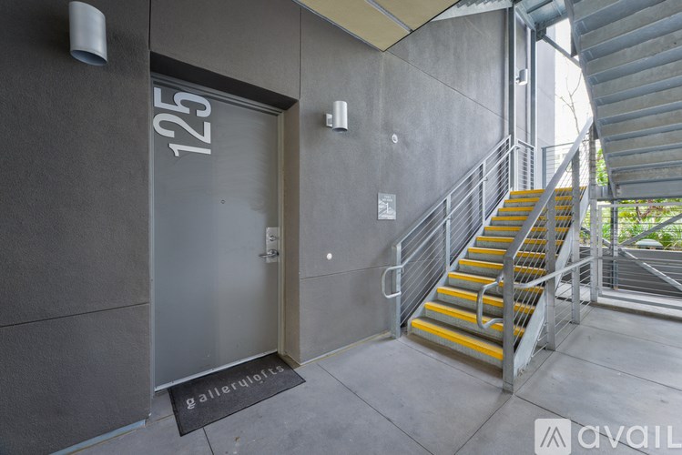 A set of stairs with yellow handrails lead up to a door with the number 125 on it.