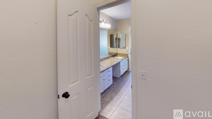 A bathroom with a sink, mirror, and cabinets is visible through an open door.