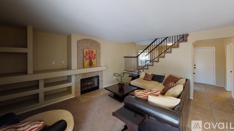 A living room with a couch, a fireplace, and a staircase.