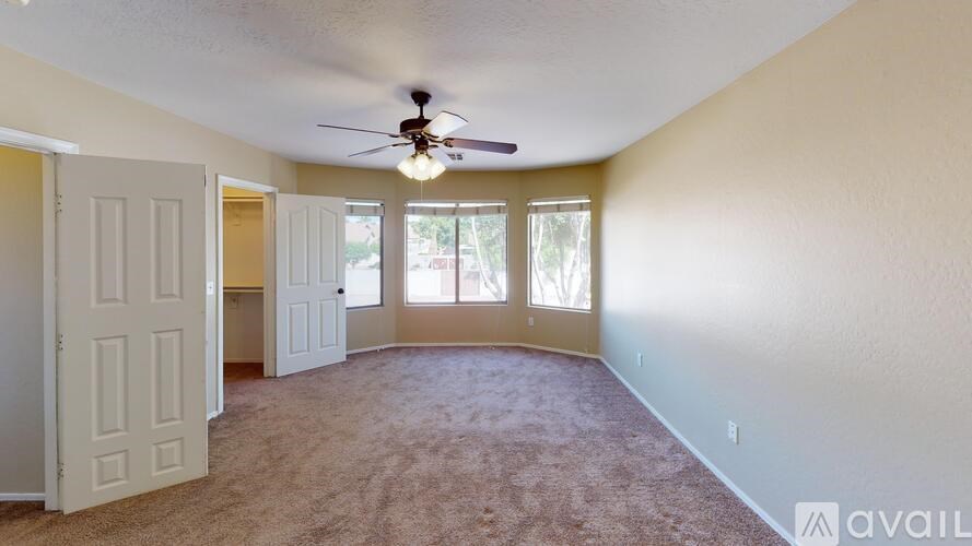 A room with a ceiling fan and carpeted floor.